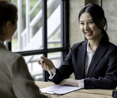 Smiling young Asian businesswomen talking to colleague and exchanging ideas together at office.